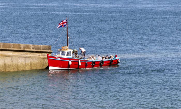 The boat Nemesis bringing visitors to Caldey Island alongside the island jetty on a sunny day.